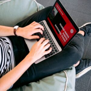 Person working remotely on a laptop while sitting comfortably on a beanbag chair indoors.